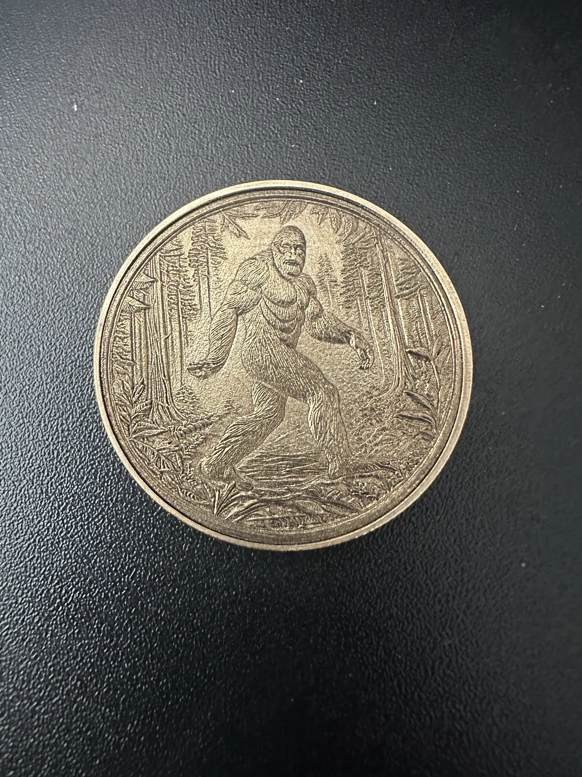 Sasquatch figure engraved into a brass coin